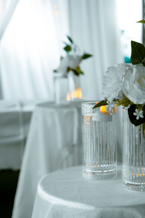 Free Elegant wedding table setup featuring white flowers and candles in a serene indoor setting. Stock Photo