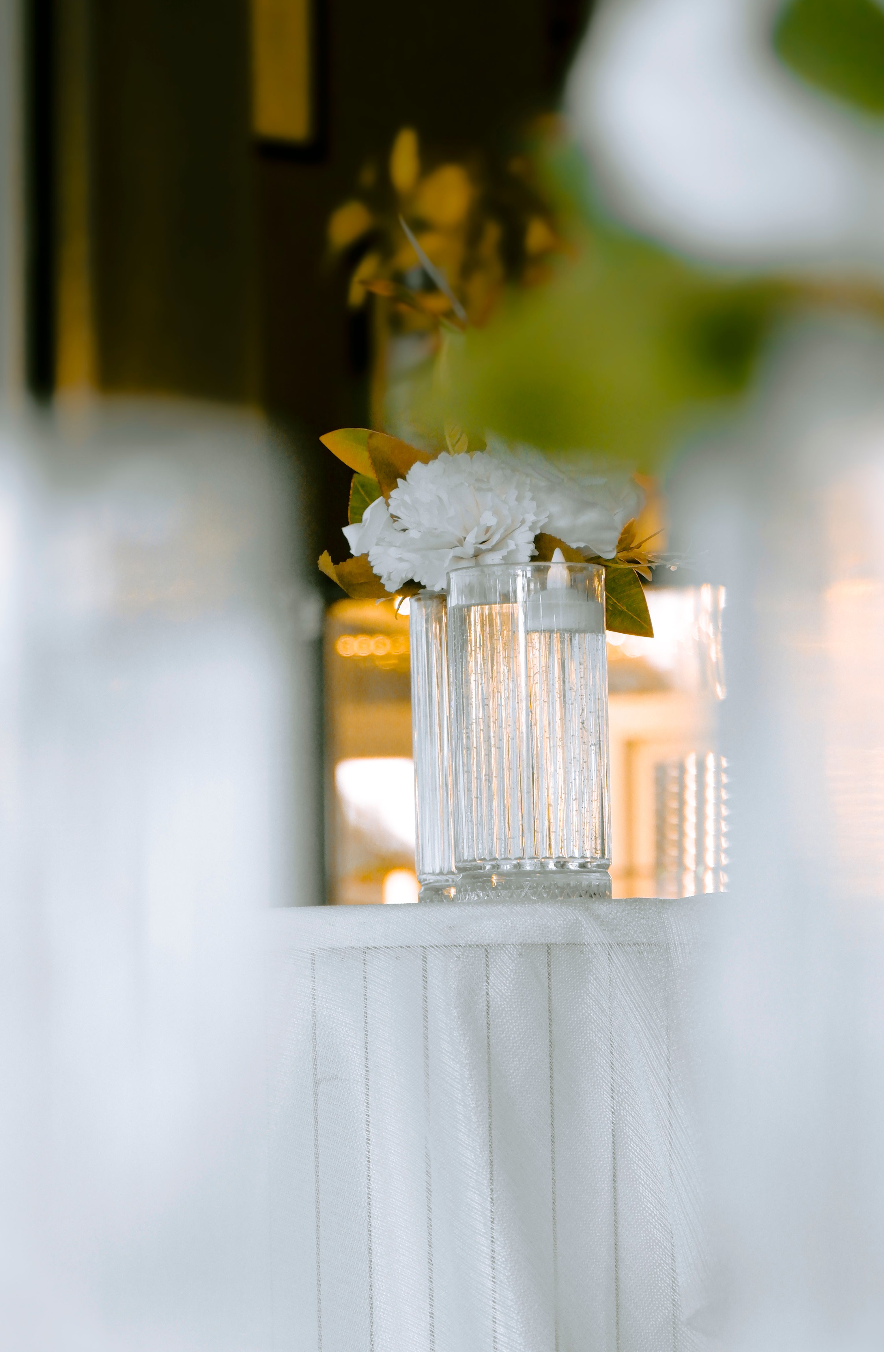 A stylish table setup featuring a white floral arrangement in a textured glass vase, creating a warm and elegant atmosphere.
