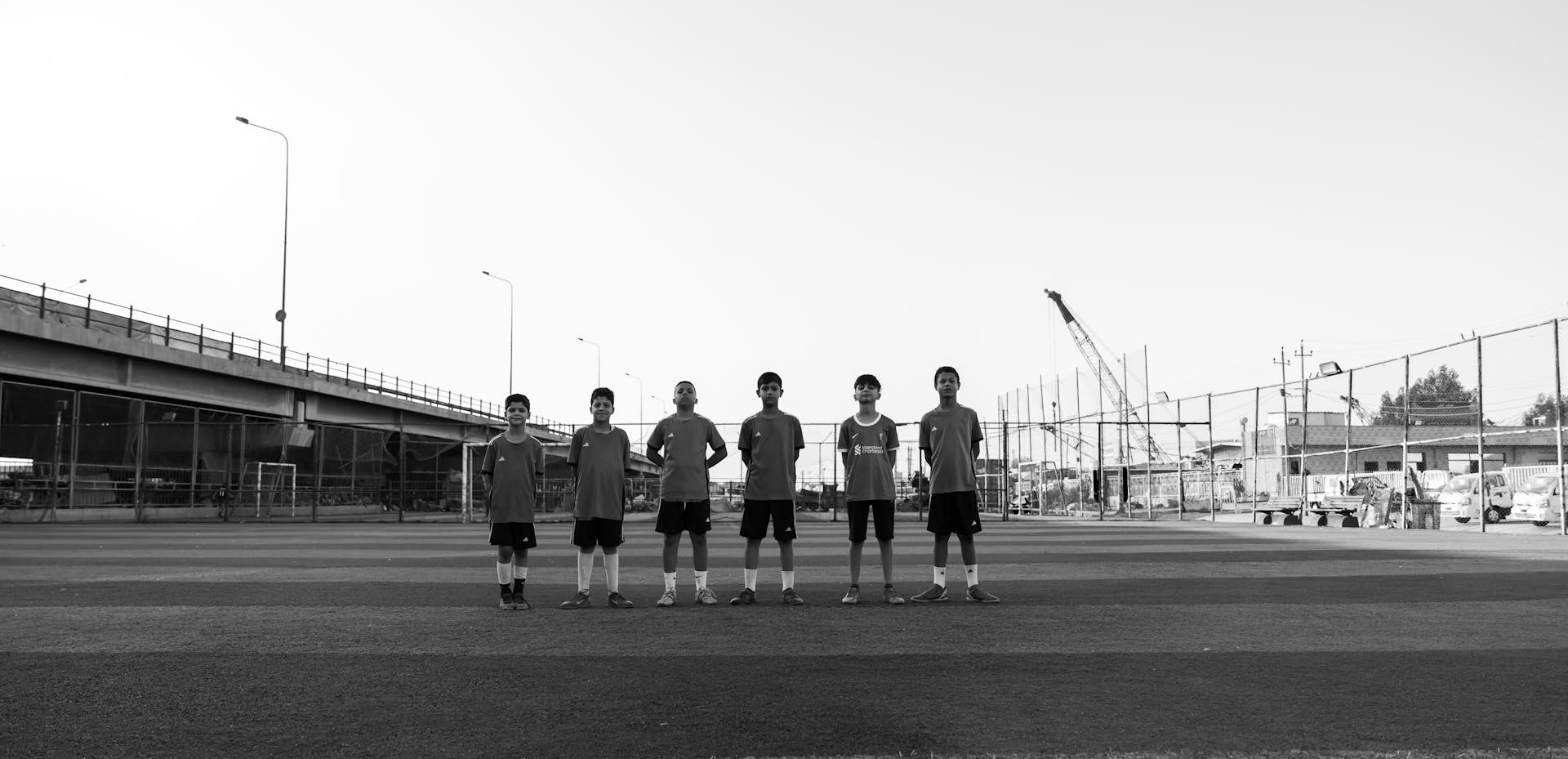 Black and white photo of a youth soccer team lined up on a field beneath an overpass.