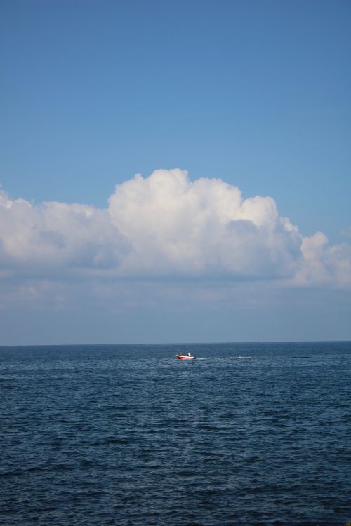 Free A tranquil view of the sea with a small boat under expansive clouds in Trabzon, Türkiye. Stock Photo