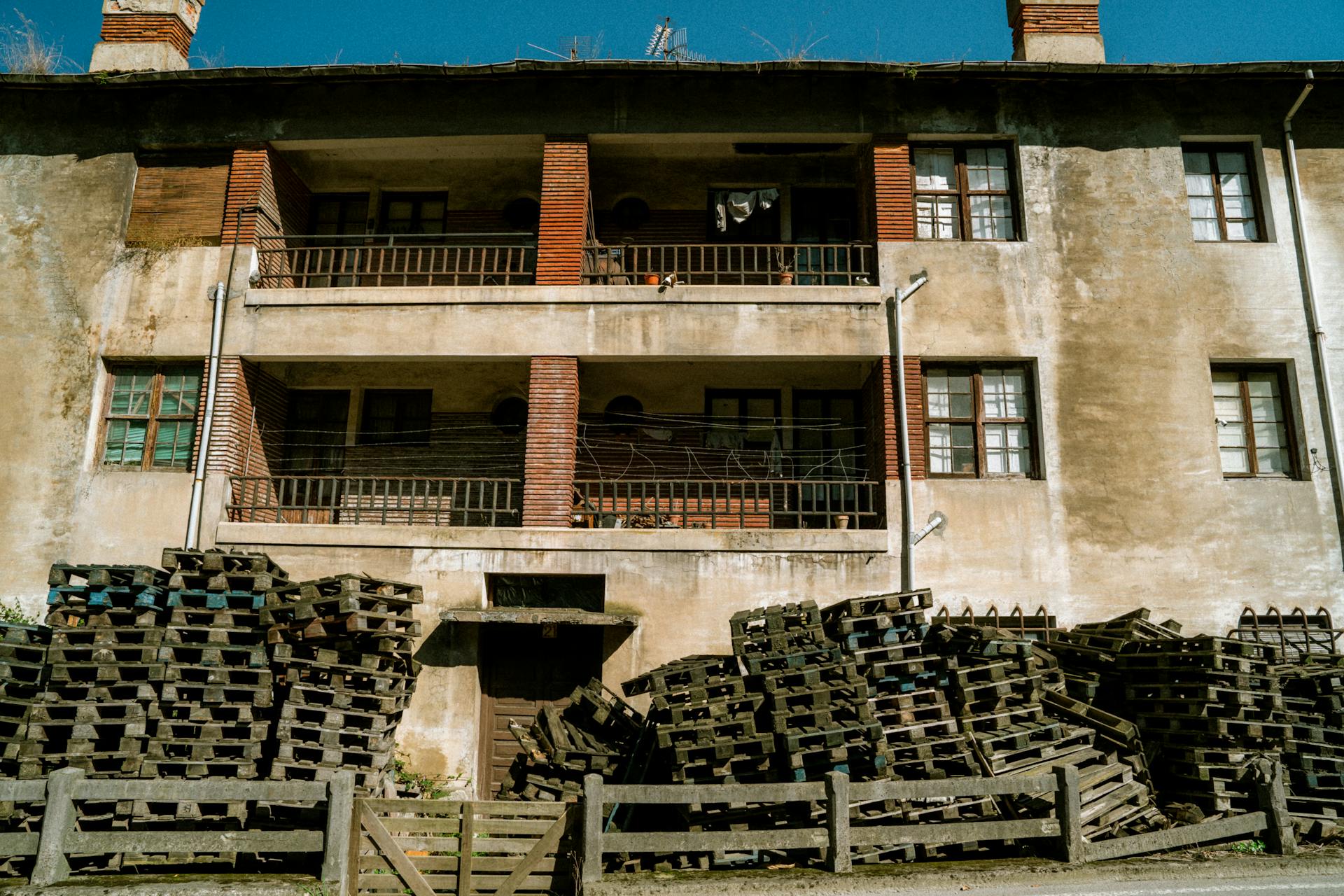 Aged building facade with wooden pallets stacked in the foreground.