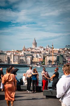 Tourists enjoying a sunny day by the Bosphorus with the iconic Galata Tower in the background.