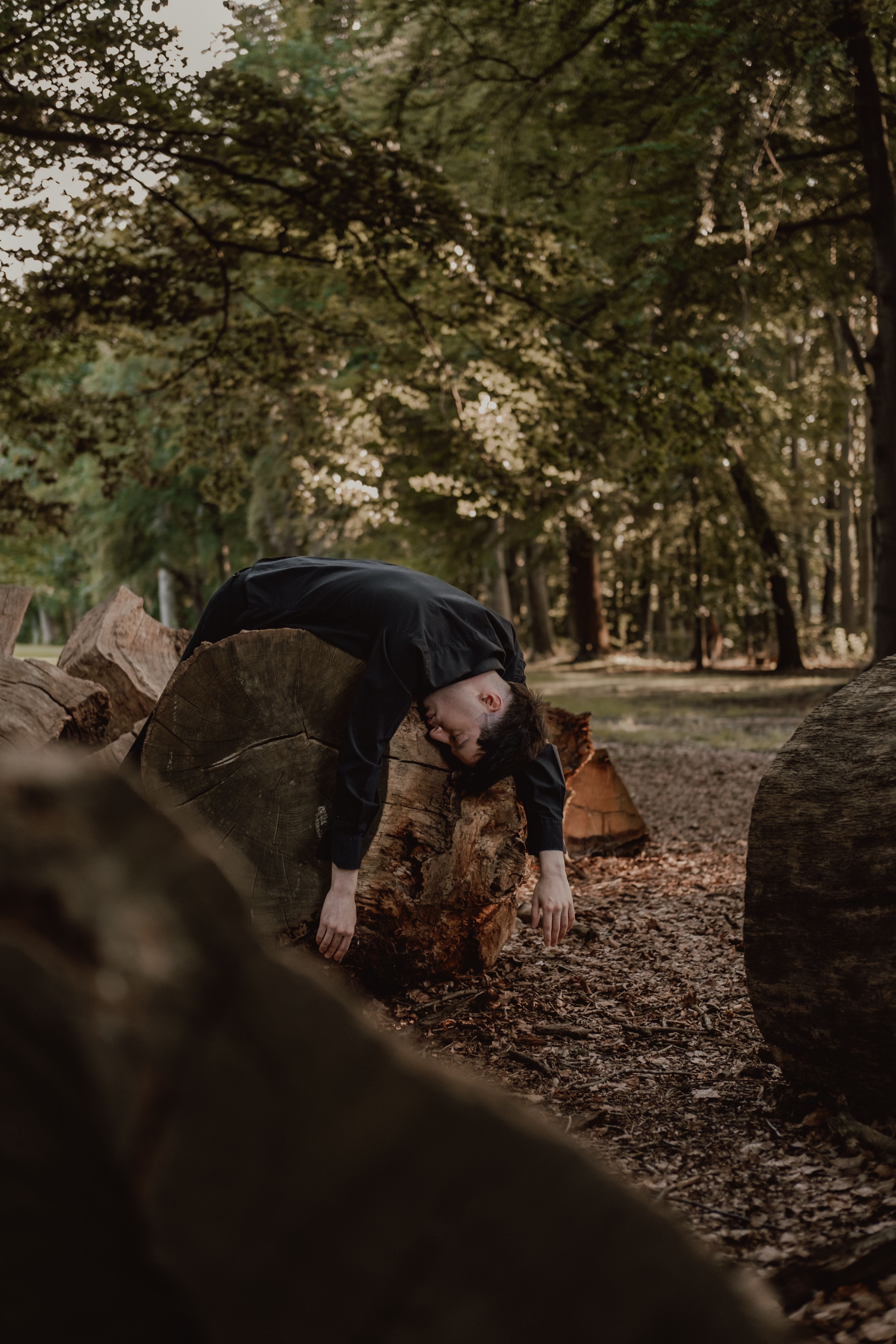 Man Resting on Fallen Log in Forest Setting · Free Stock Photo