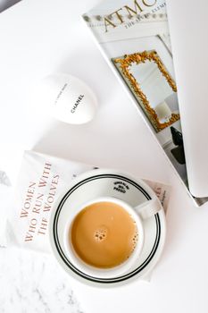 Elegant coffee scene with books and Chanel item on a white table for lifestyle inspiration.