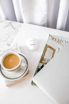 Elegant flat lay featuring coffee, magazine, and decor on a marble surface.
