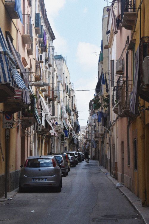 Free Quaint narrow street lined with classic European buildings and cars, evoking a sense of history. Stock Photo