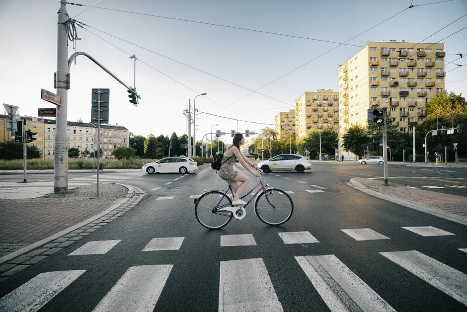 Woman on bicycle crossing intersection in Wroclaw, Poland during the day.