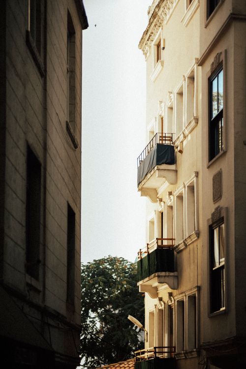Free A beautifully lit view of city buildings and balconies in a narrow urban alleyway. Stock Photo