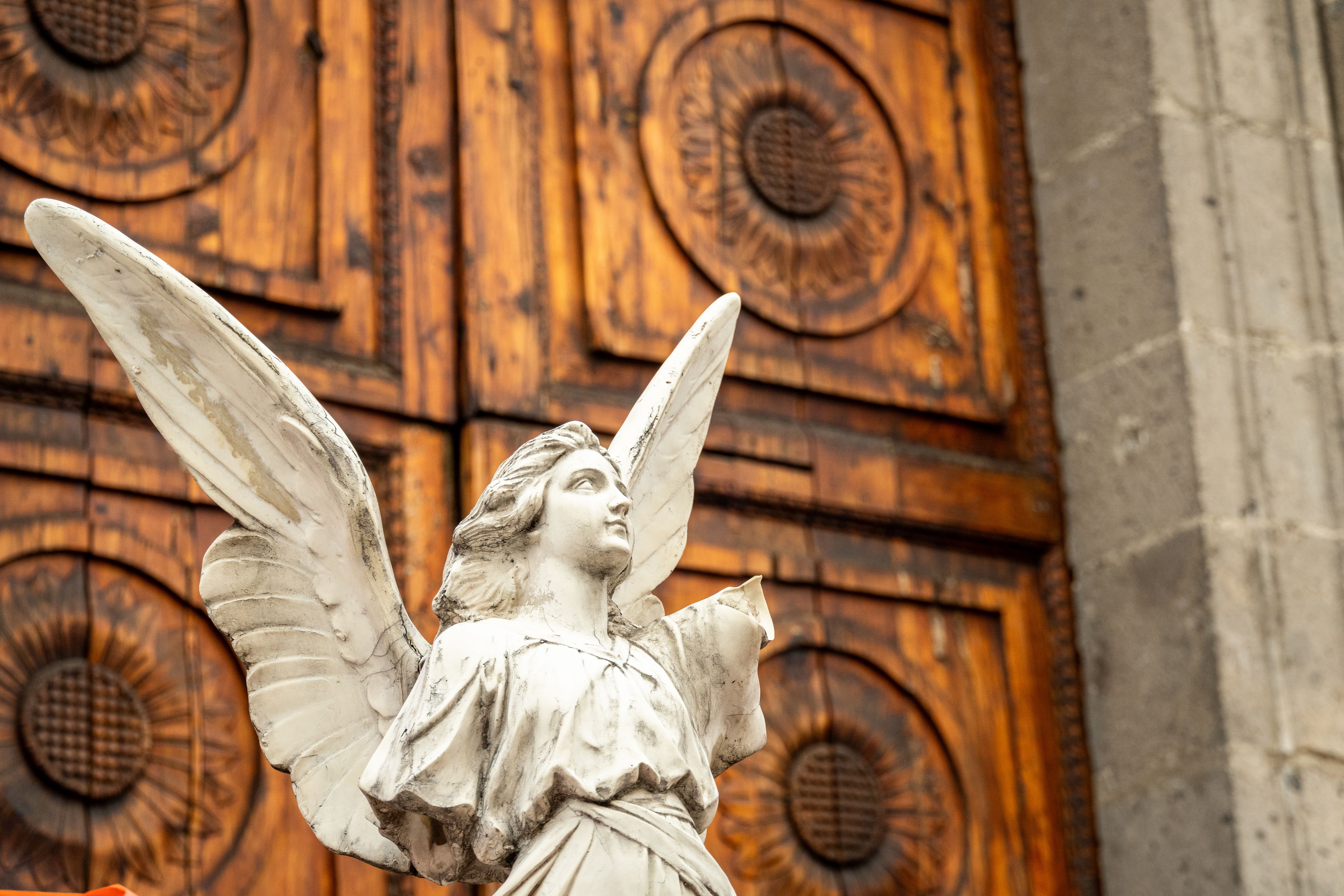 Detailed white angel sculpture outside a historic building in Mexico City.