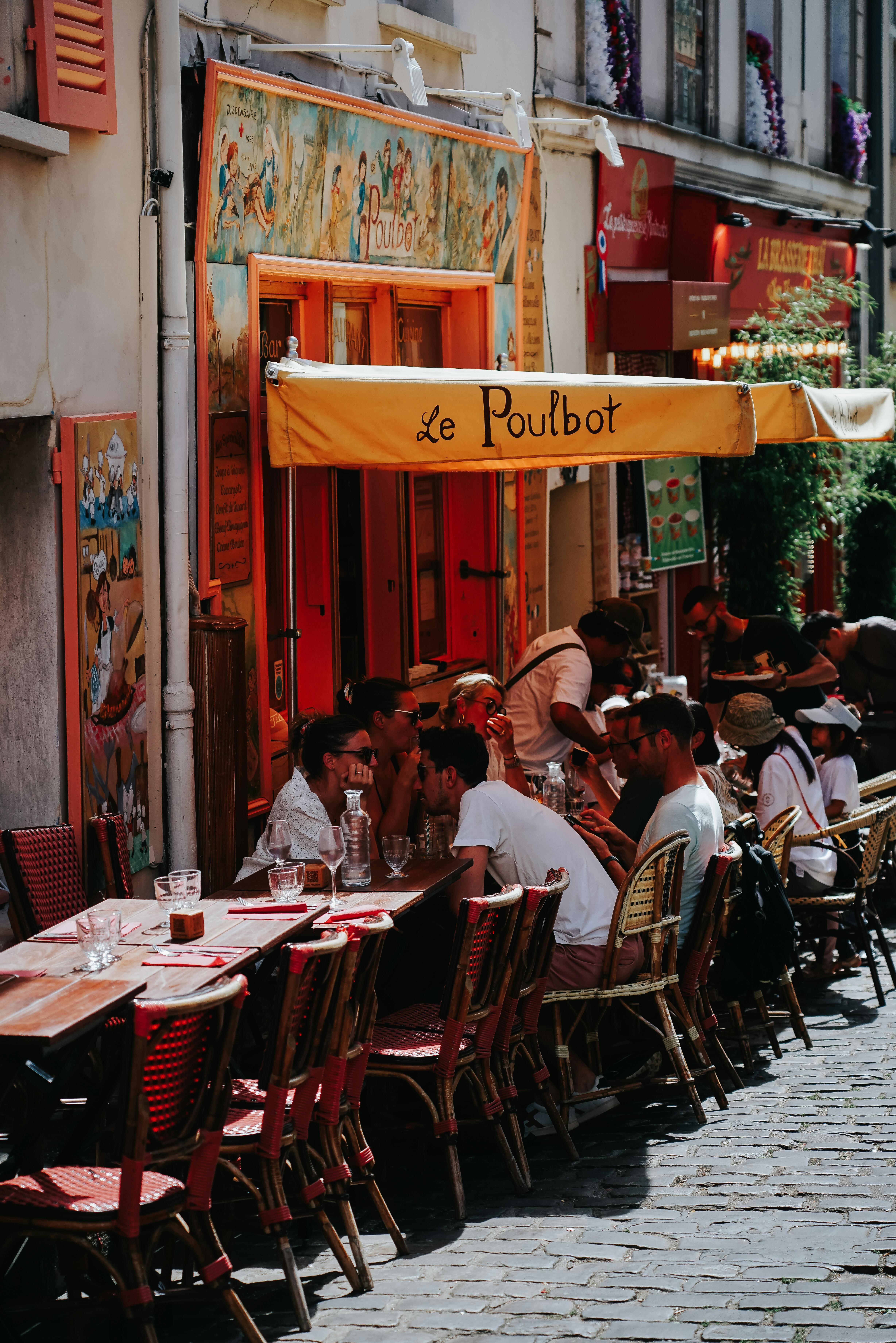 A vibrant outdoor café in Montmartre, Paris with patrons enjoying the summer day.
