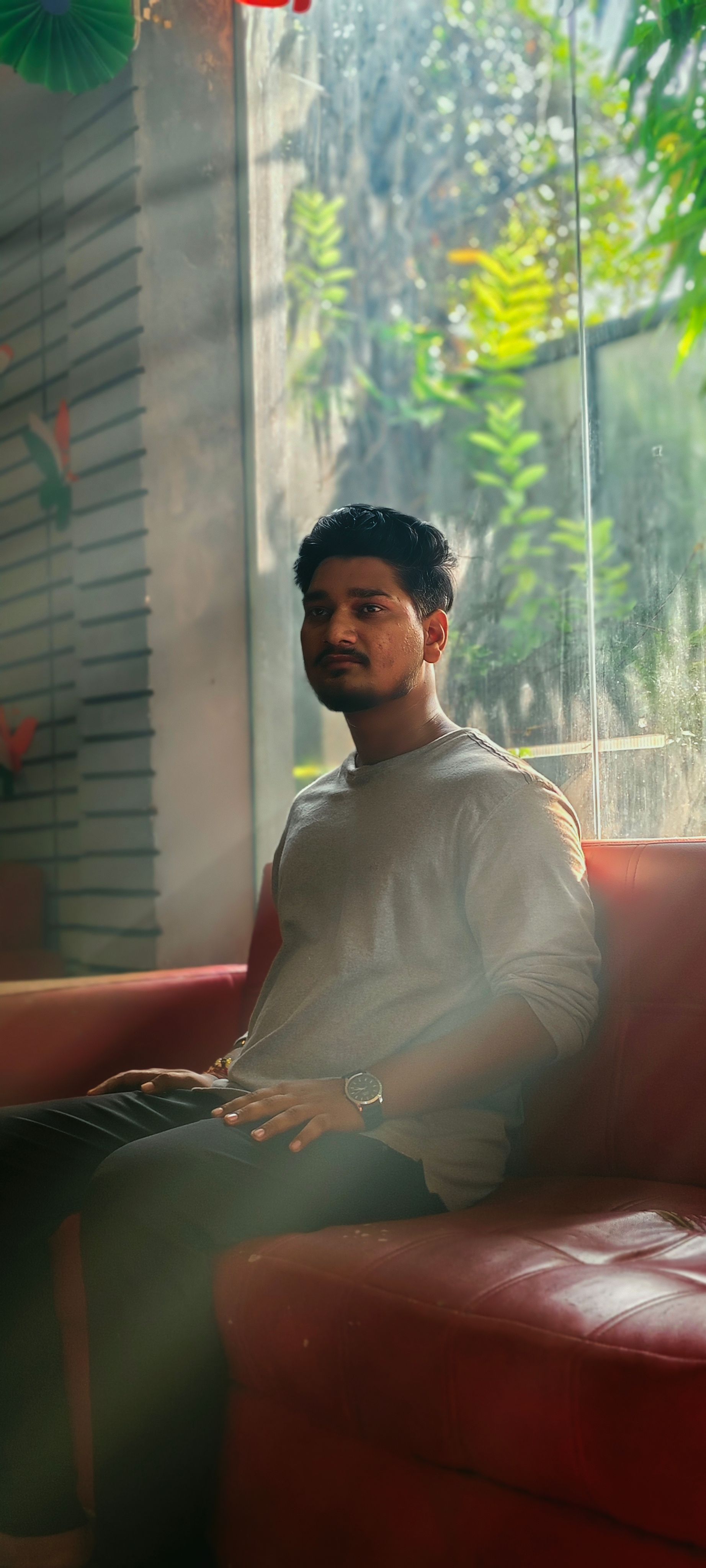 Young man sitting on a sofa by a sunlit window in a modern interior.