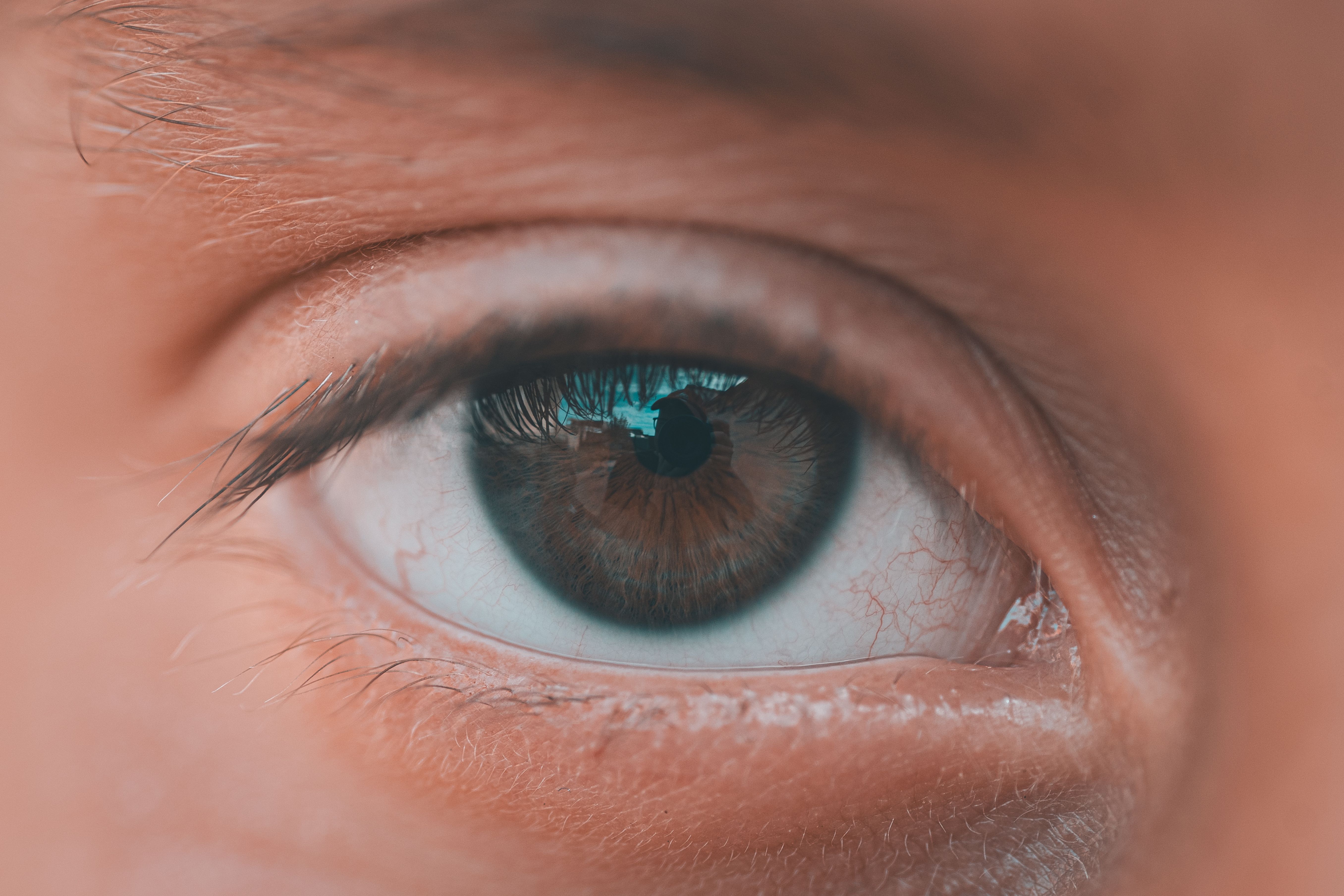 Indian person doing eye exercises while sitting at a desk with a laptop