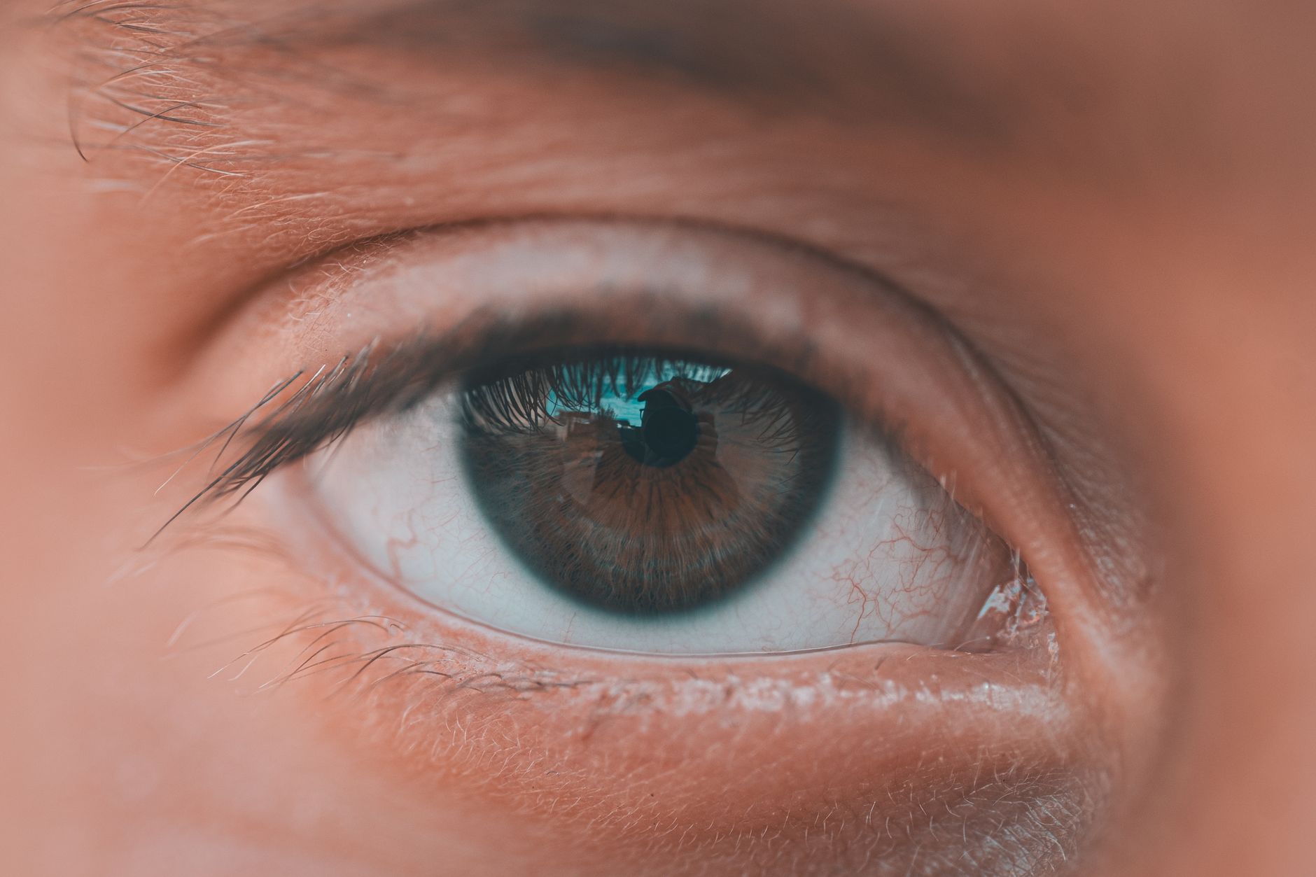 Indian person doing eye exercises while sitting at a desk with a laptop