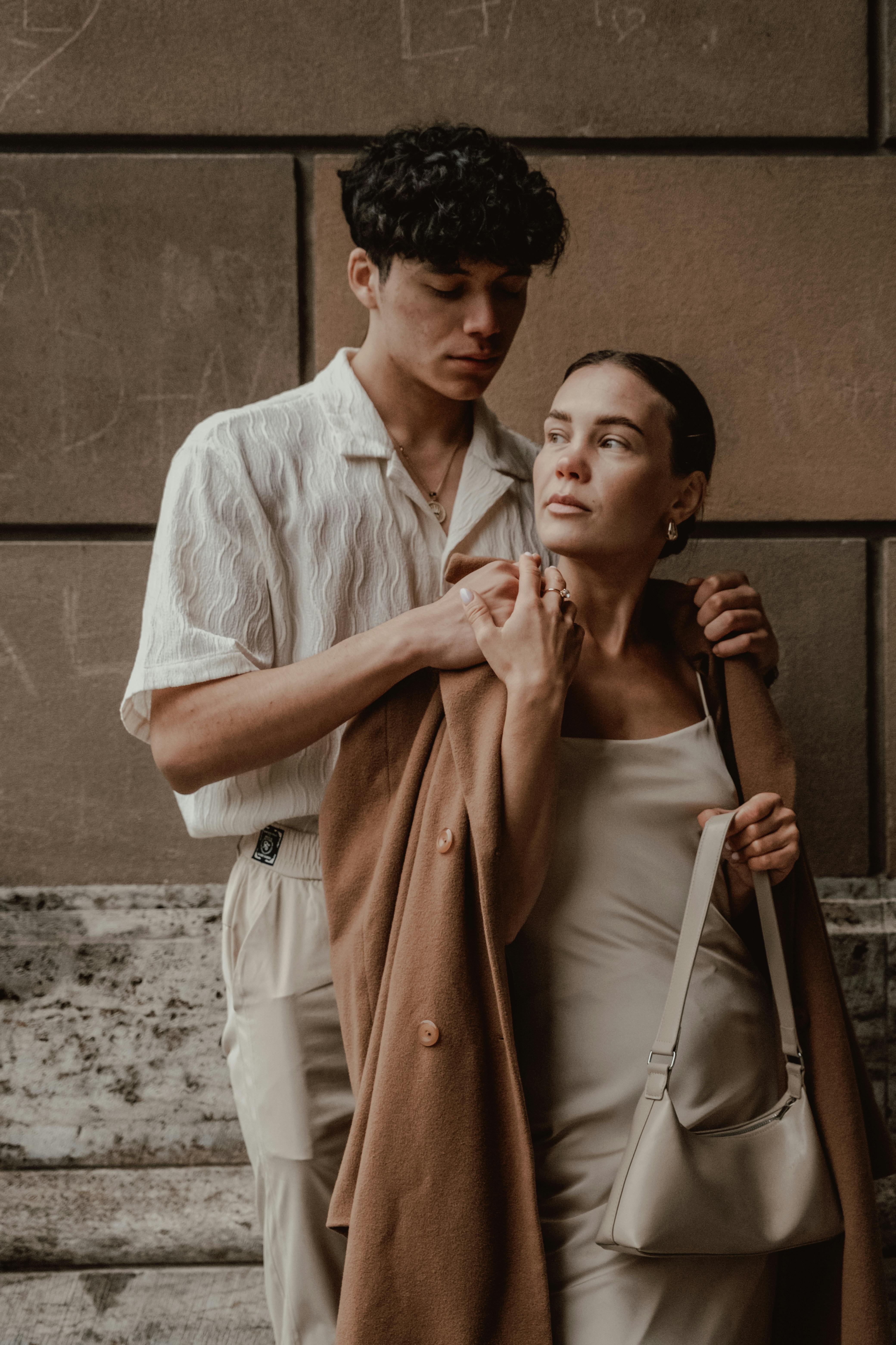 Young couple in fashionable attire embracing outdoors, displaying affection.