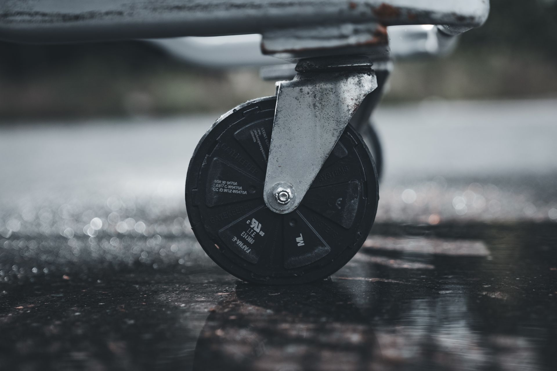 Close-up photo of a metal caster wheel on a wet surface, showcasing industrial design.