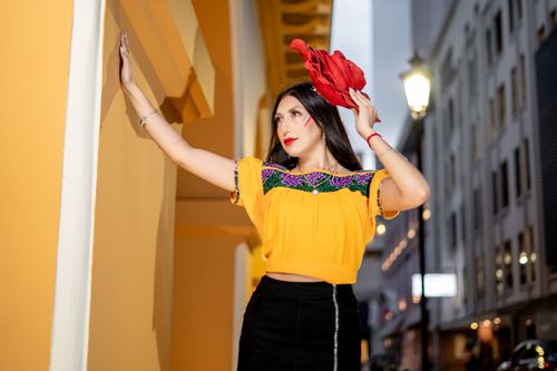 Free Elegant woman in vibrant traditional attire posing under street lights in urban setting. Stock Photo