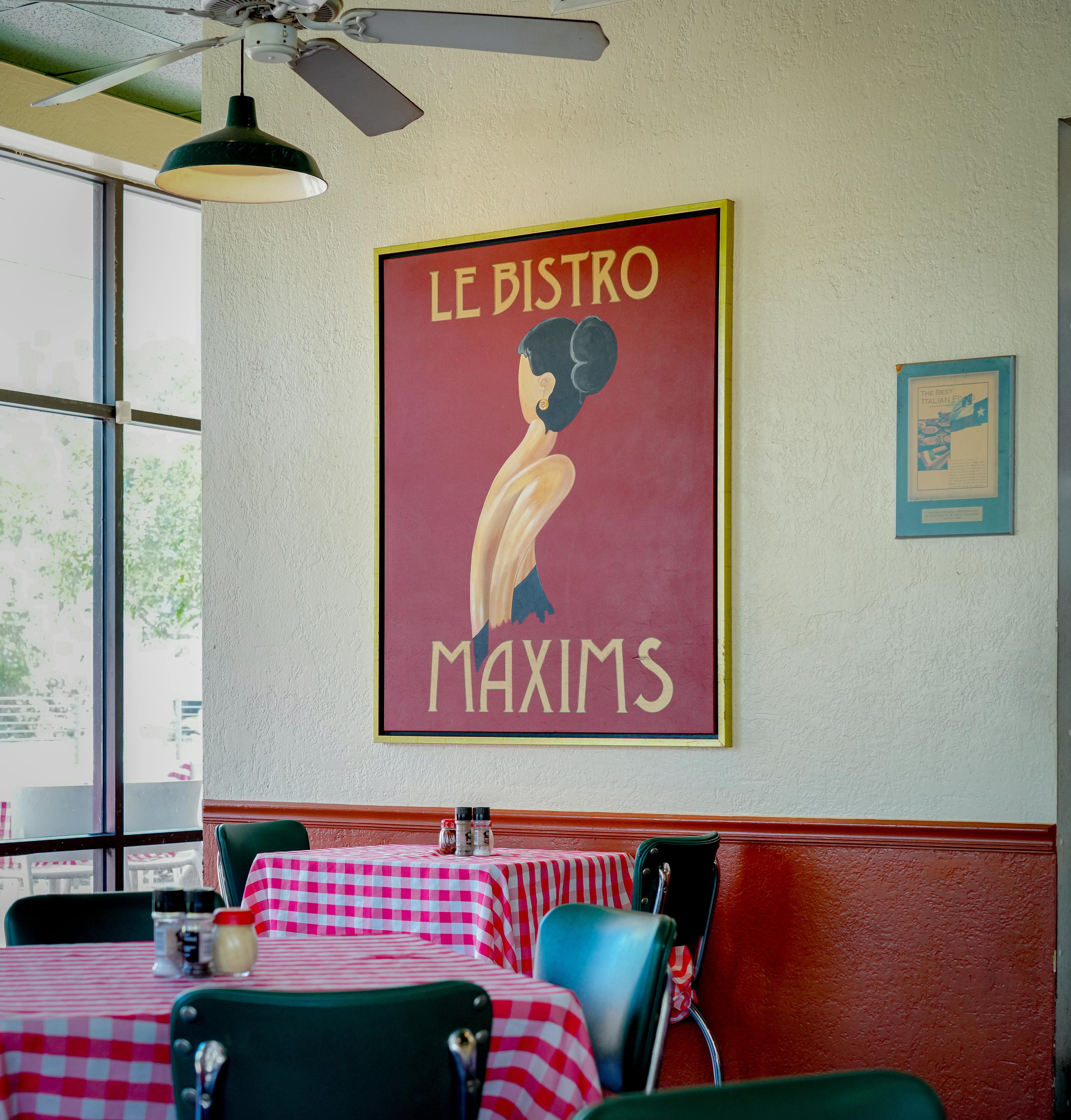 Cozy bistro in Houston with vintage poster and checkered tablecloths.