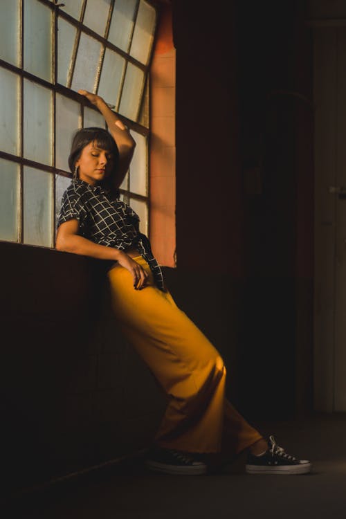 Photo of Woman Leaning Backwards by a Window With Her Eyes Closed