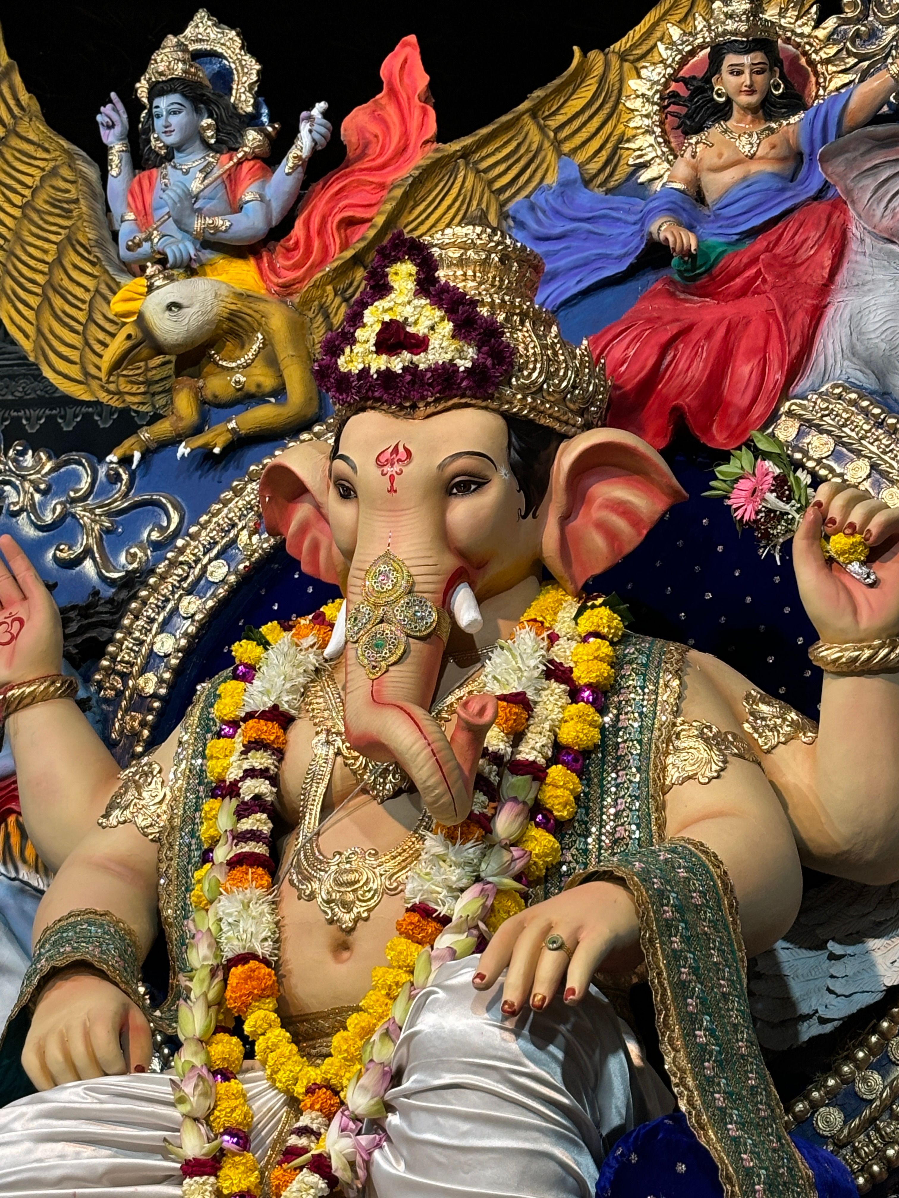 Intricate statue of Lord Ganesh adorned with colorful flowers during Ganesh Chaturthi festival.