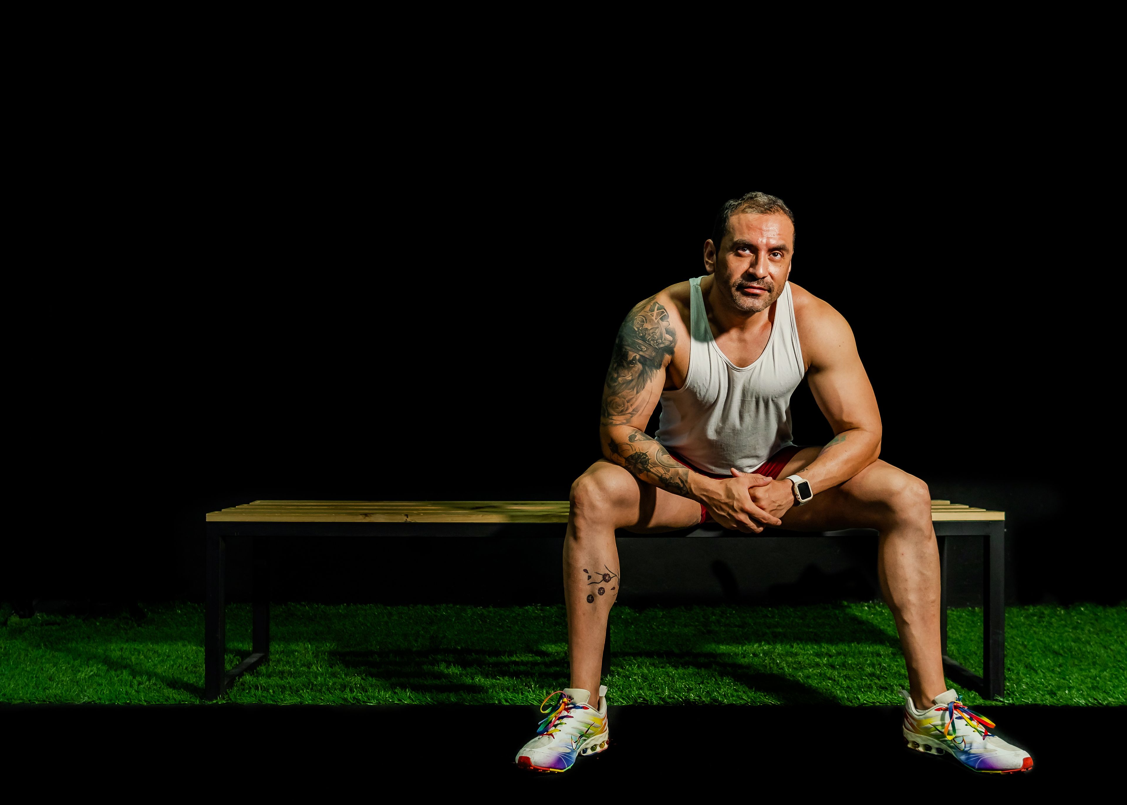 Fit male athlete in gym resting on bench, showcasing strength and motivation.