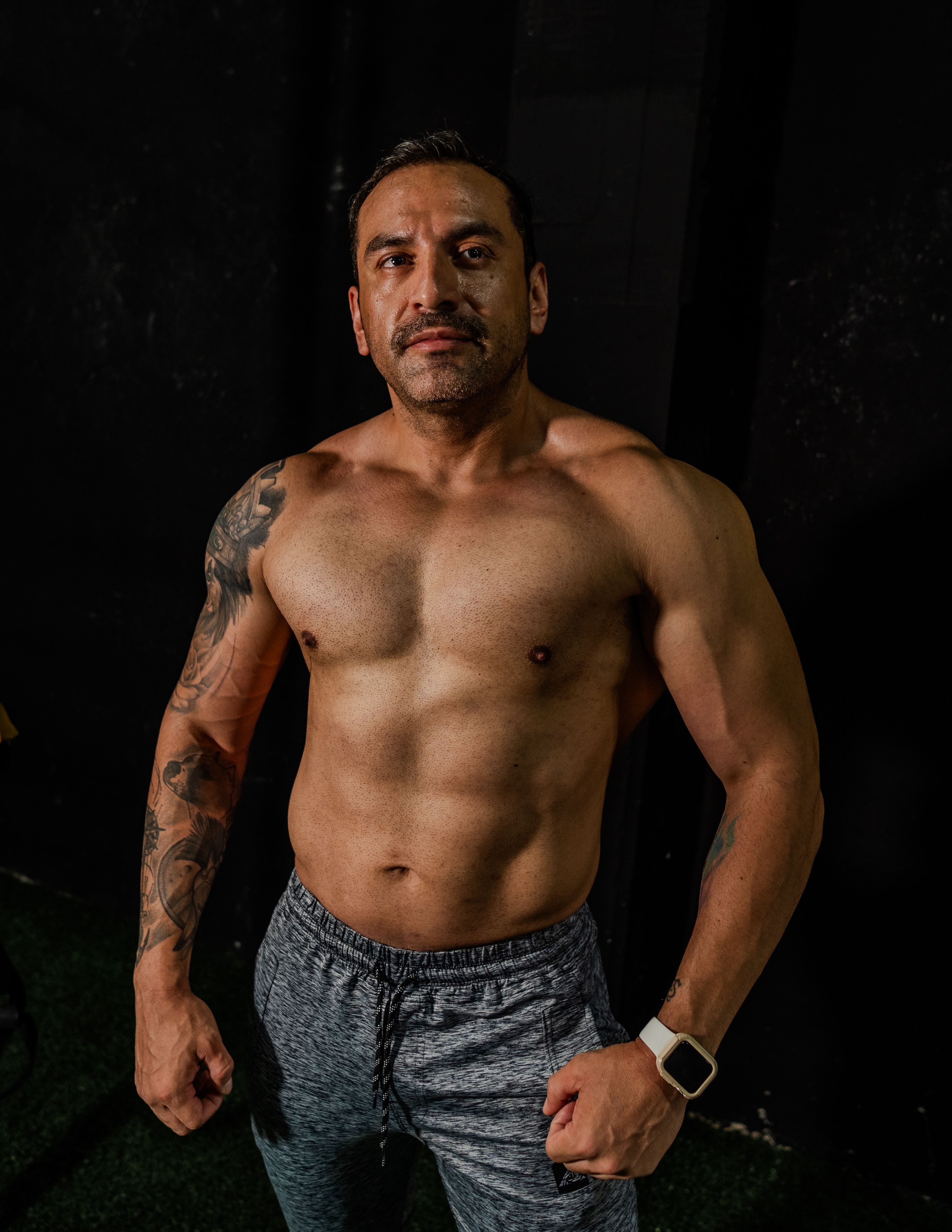 Strong muscular man confidently posing in an indoor gym setting, emphasizing fitness and strength.