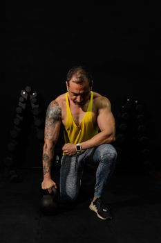 Man exercising with kettlebell in a dark gym setting, showcasing strength and focus.