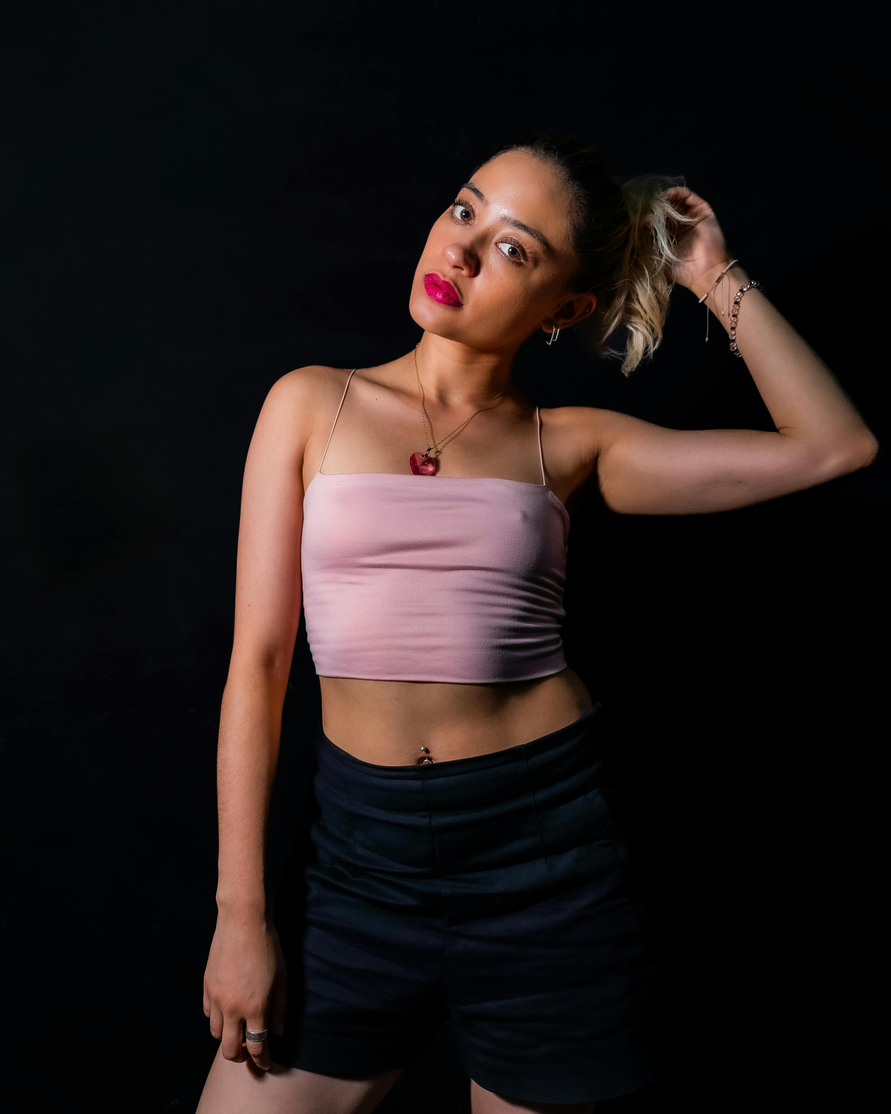Free Elegant studio portrait of a young woman posing against a dark background, showcasing fashion and style. Stock Photo
