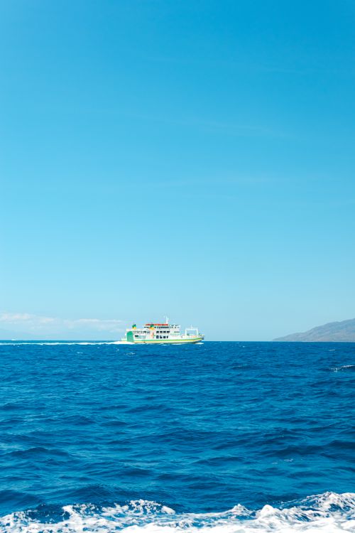 Free A ferry boat sailing on clear ocean waters with a bright blue sky. Stock Photo