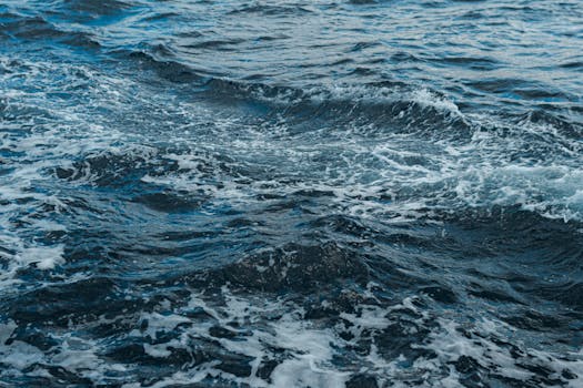 Close-up shot of swirling ocean waves and white foam, showing natural movement.