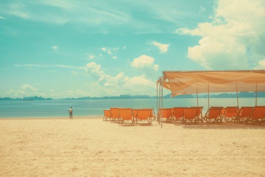 Relaxing empty beach with sun loungers and a man in the distance.