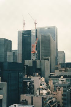 Tokyo cityscape featuring skyscrapers and construction cranes.