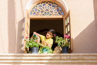 Young boy watering plants in a traditional Persian window in Yazd, Iran.