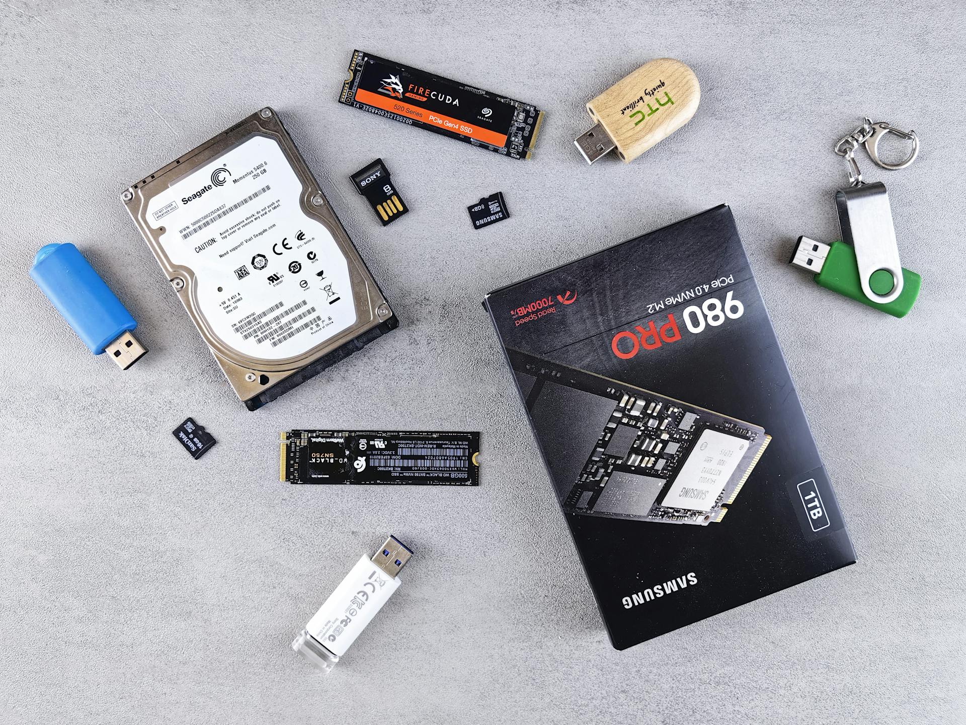 Flat lay of various computer data storage devices on a gray surface.