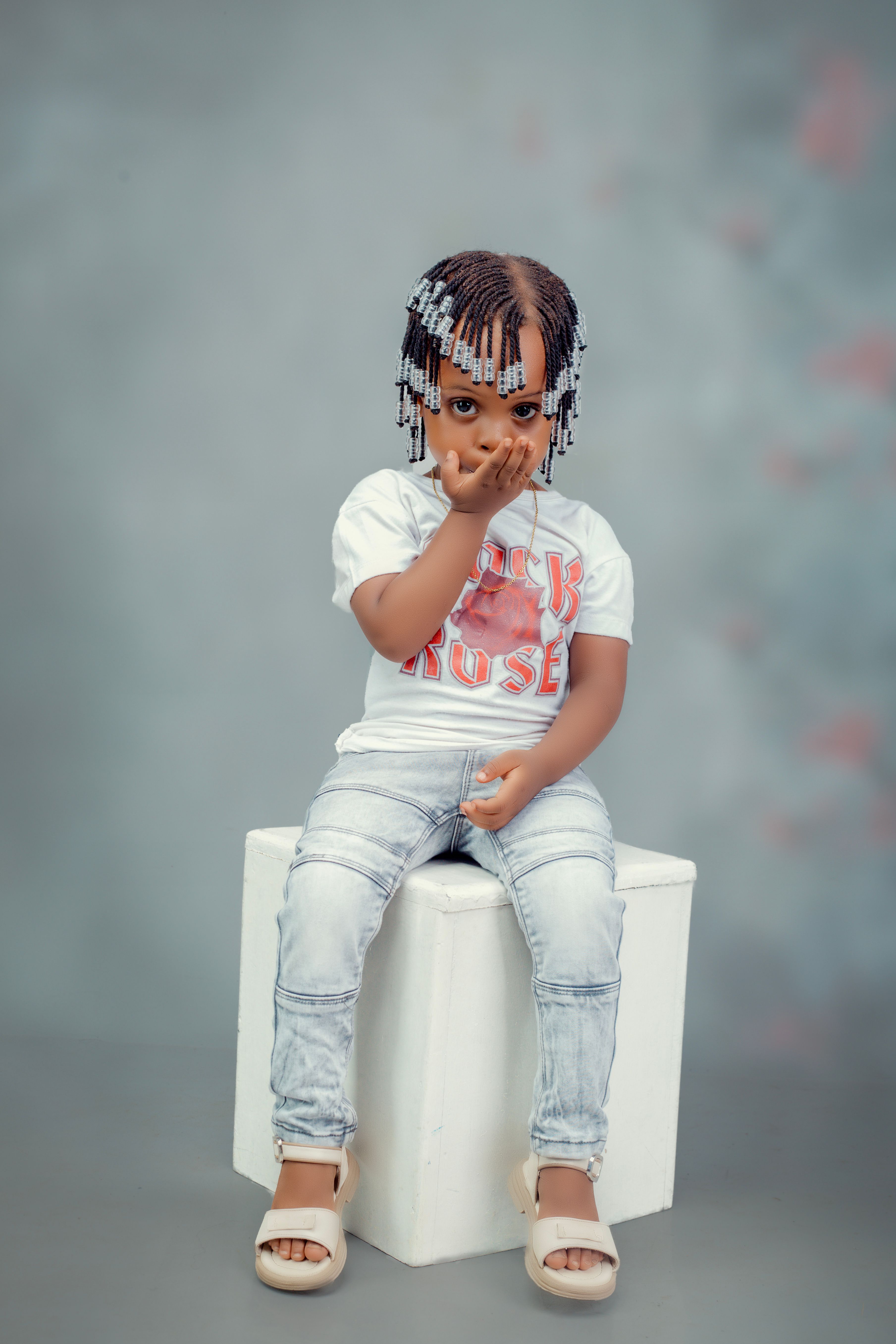 Charming young child posing confidently indoors, showcasing unique fashion and hairstyle.