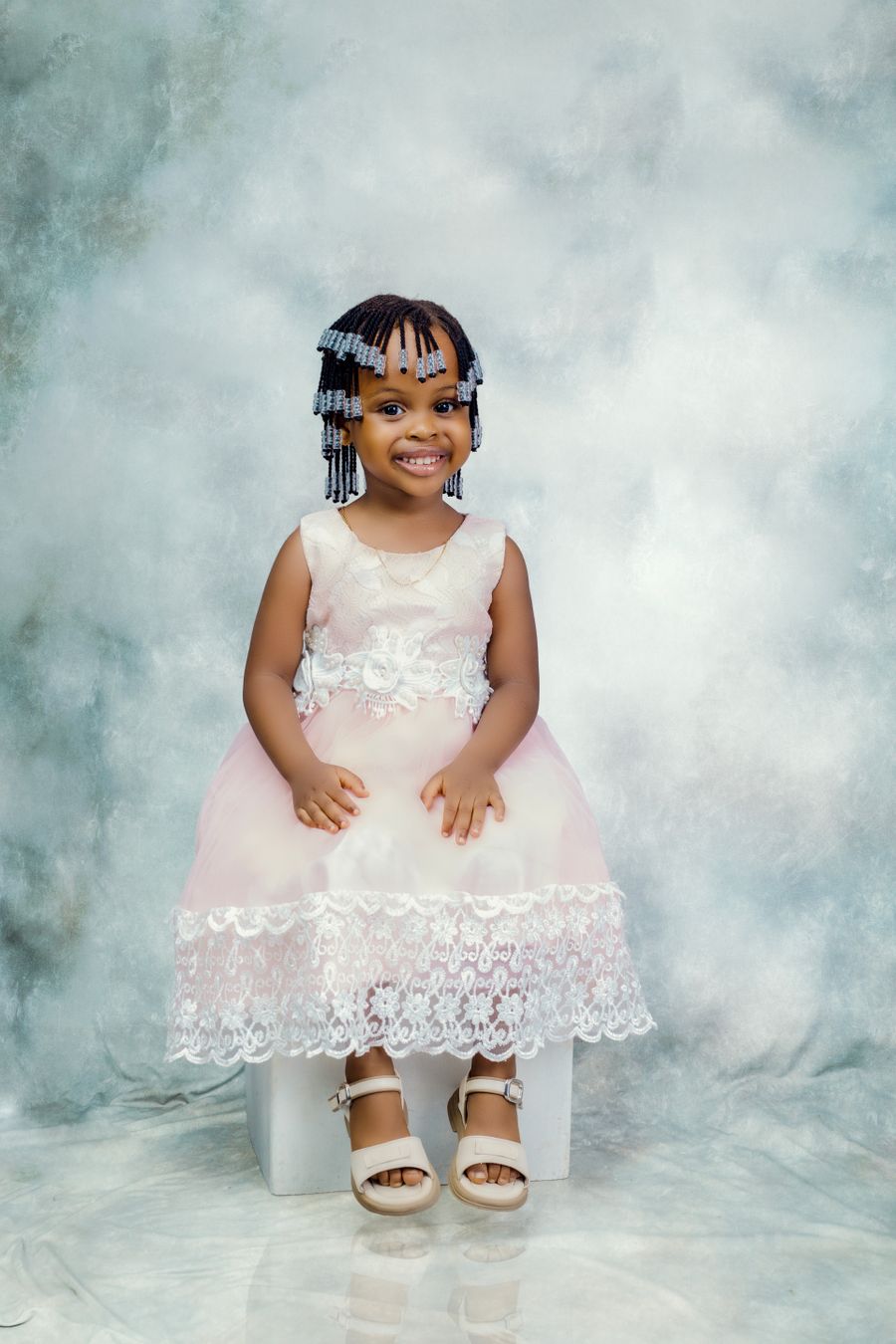 Child in an elegant pink lace dress, smiling
