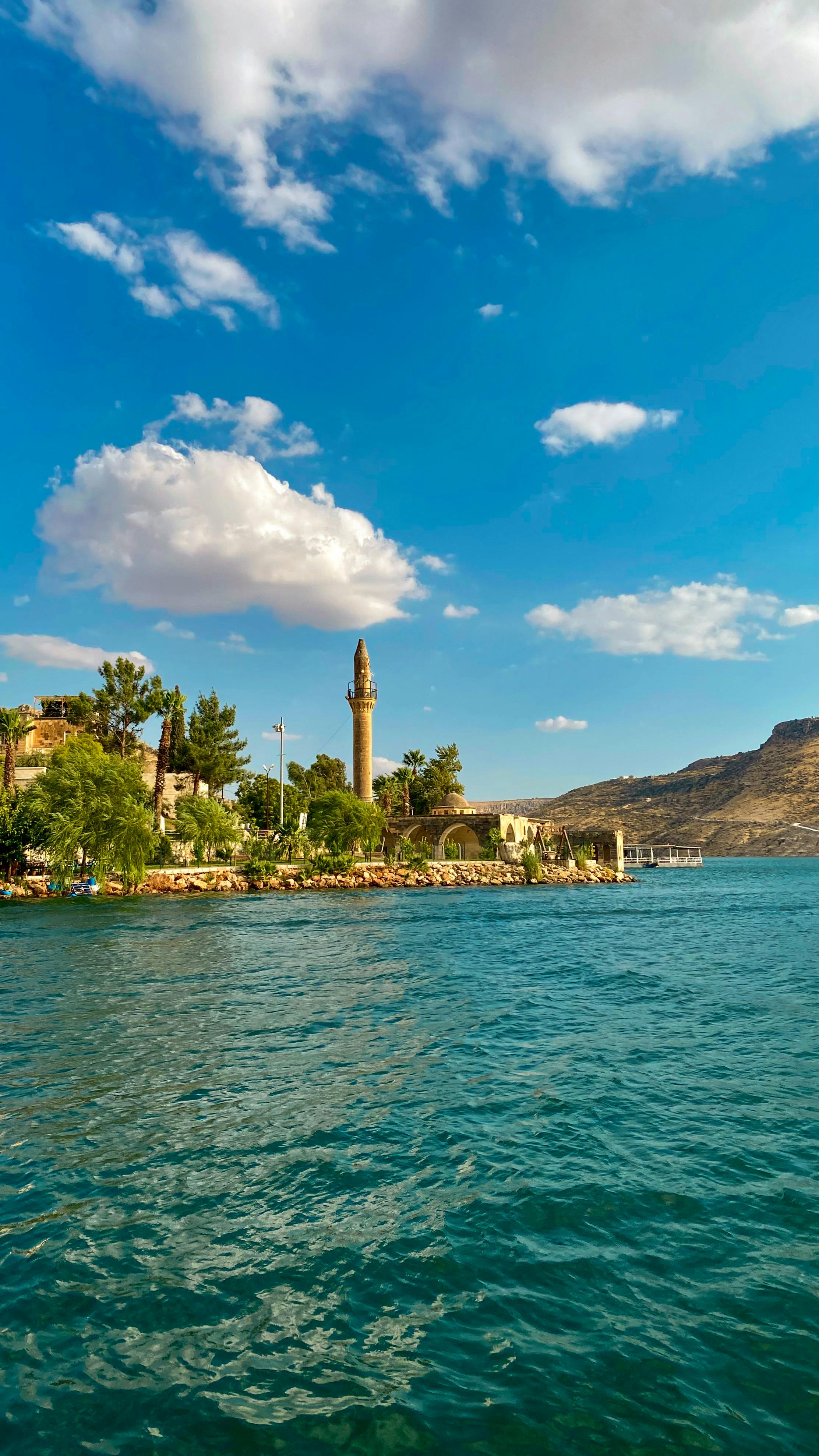 Picturesque river scene in Halfeti, Turkey with a minaret and clear blue skies.