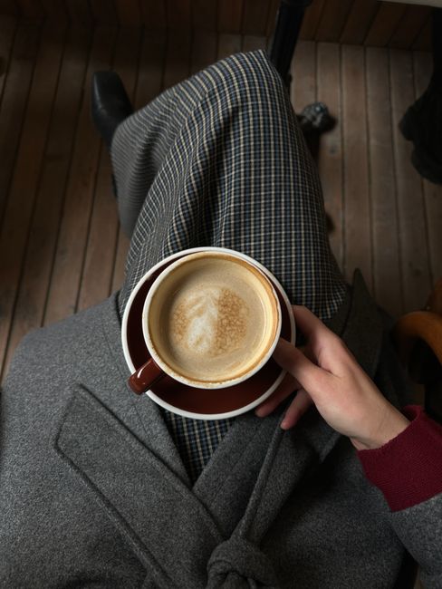 Enjoying a warm cappuccino during a peaceful autumn morning indoors.