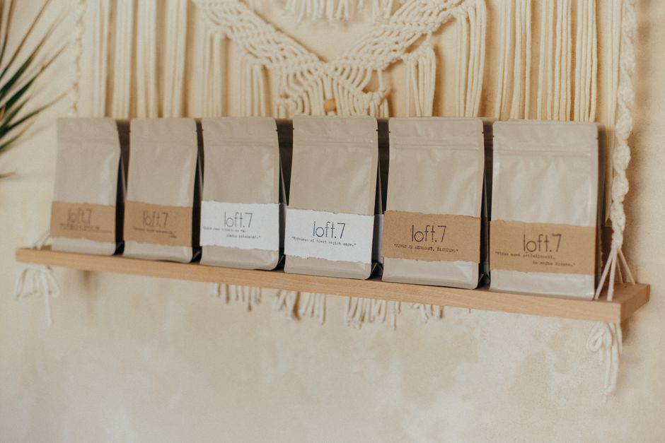 coffee bags lined up on wooden shelf in roastery, warm light
