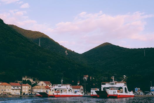 Explore Montenegro's serene harbor with boats docked beneath towering mountains. A perfect summer setting. by Maksim Dyachuk