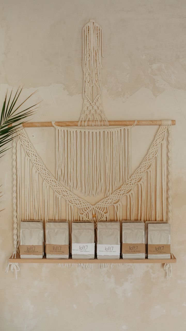 Knotted cotton macramé wall hanging displayed behind a small boho coffee bar with ceramic mugs