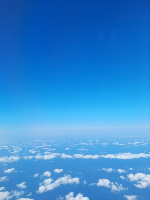 Free A peaceful aerial view showcasing a clear blue sky and fluffy white clouds. Stock Photo
