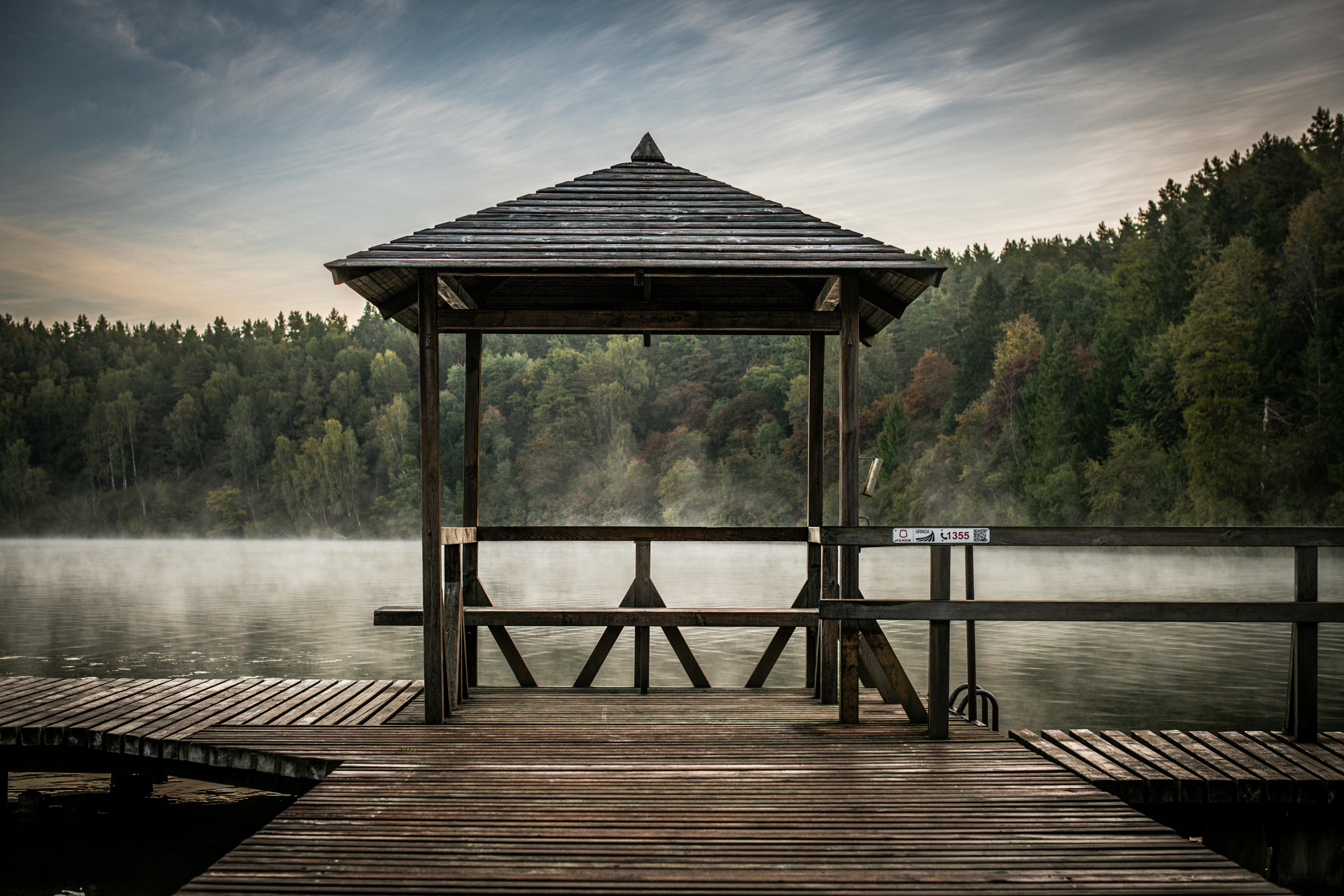 A tranquil lakeside scene featuring a wooden gazebo surrounded by lush forest in Vilnius, Lithuania.