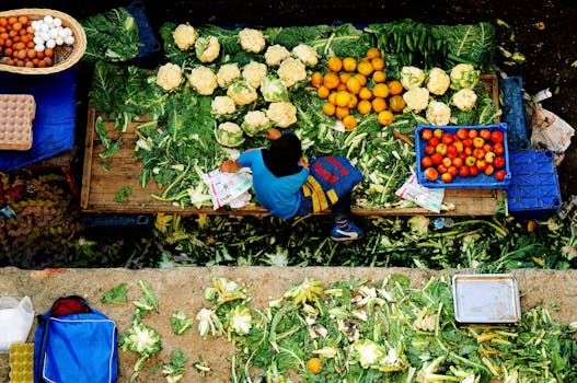 Young vendor at a vibrant market stall in İzmir, Türkiye, displaying fresh produce from above.
