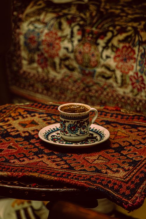 Free A cup of Turkish coffee in a decorative cup on an intricately patterned tapestry, evoking a warm, cultural ambience. Stock Photo