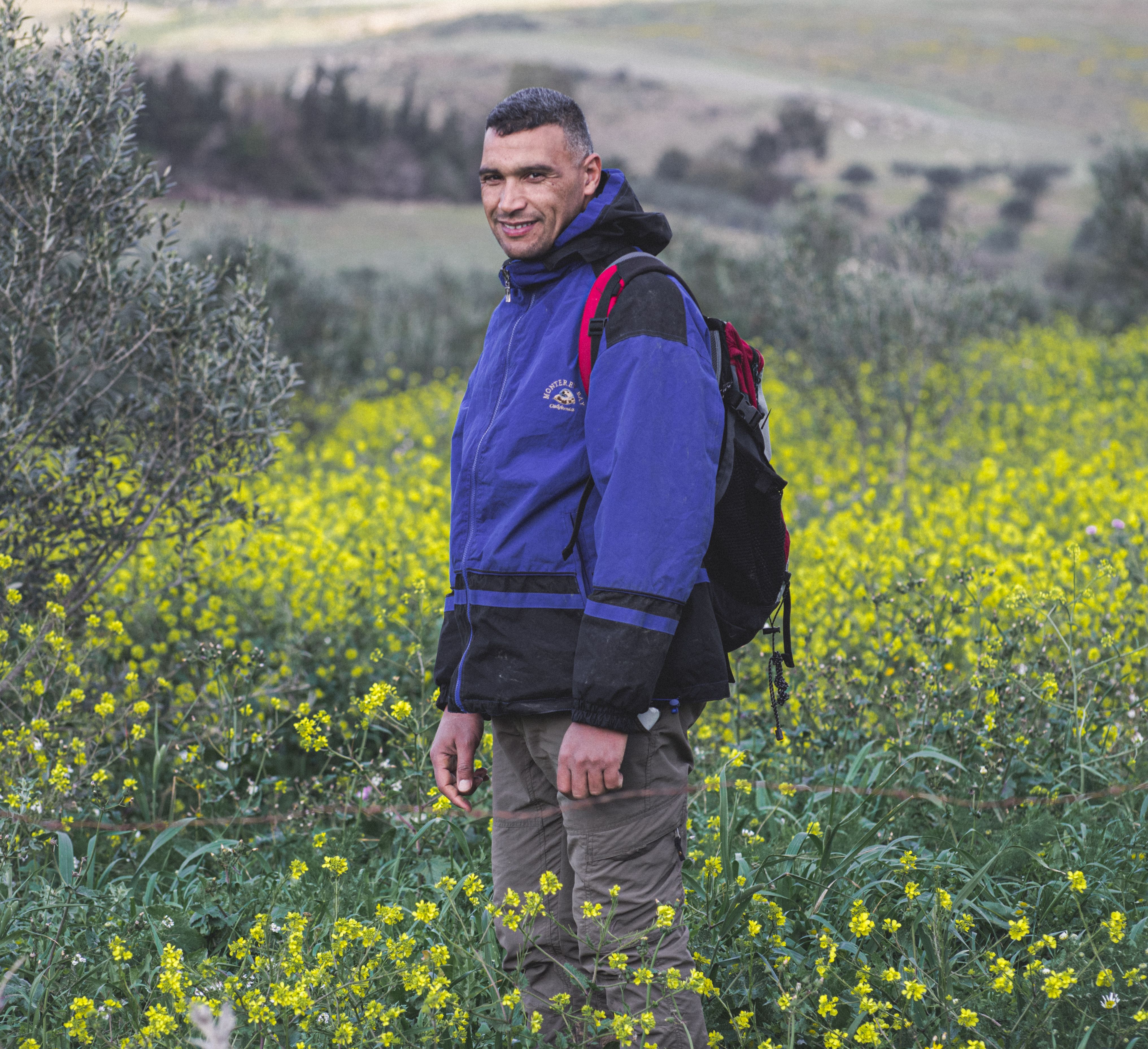 A man hiking through yellow fields in Bou Argoub, Tunisia, on a bright day.