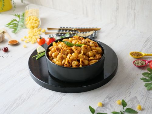 Free Spicy Indian masala pasta served in a black bowl with fresh ingredients and spices. Stock Photo