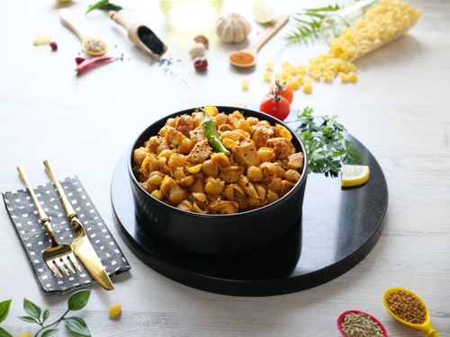 Free A bowl of spicy pasta on a black plate with ingredients around it, ready to serve. Stock Photo