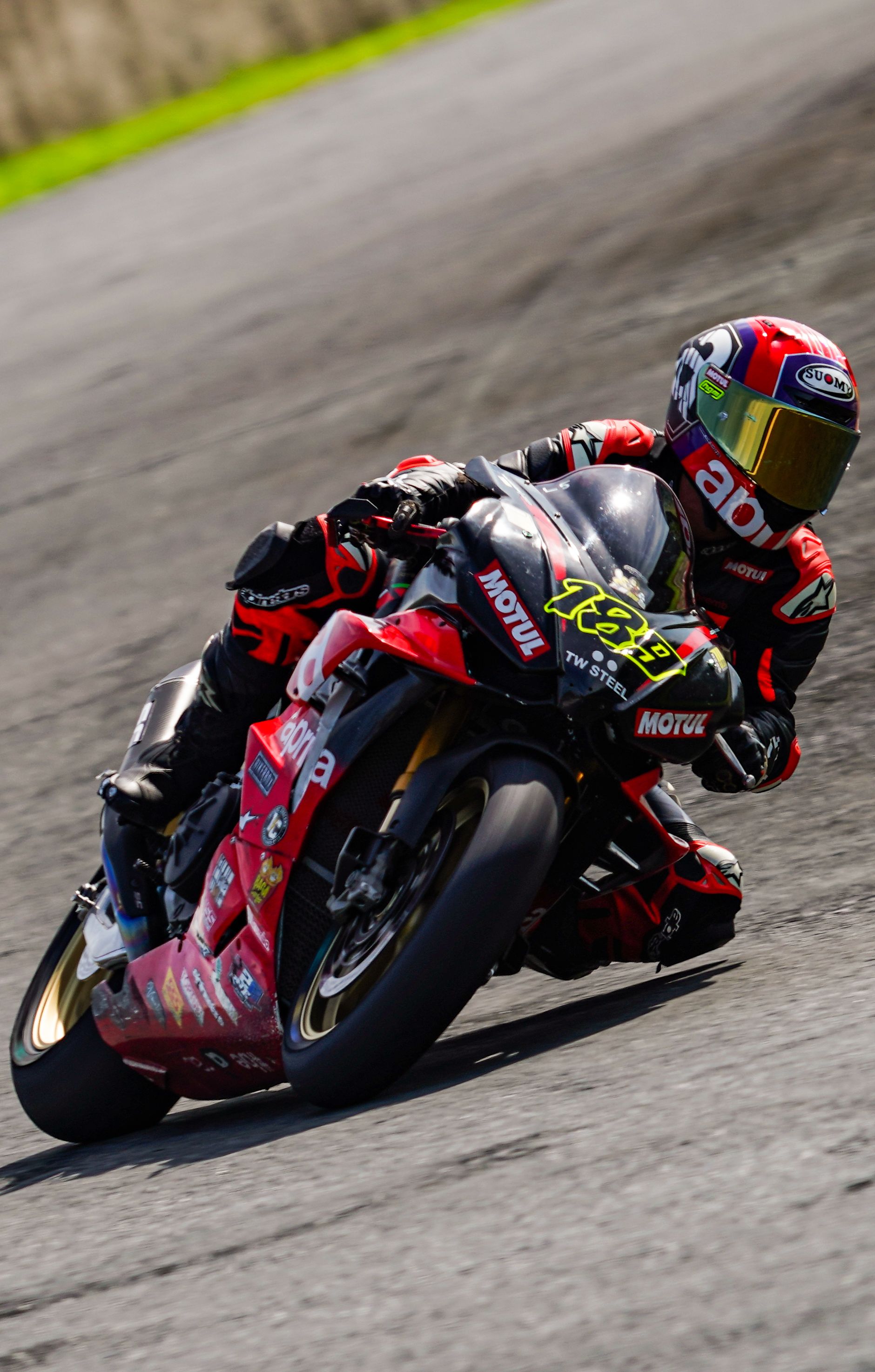 Motorcycle racer leans into a turn on a track, emphasizing speed and focus.