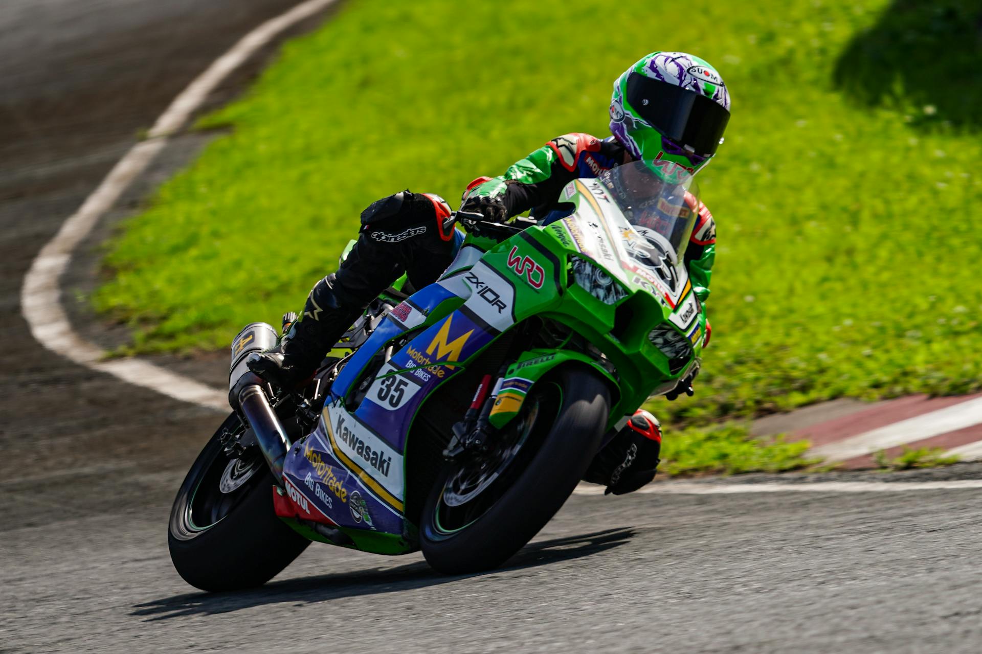 A motorcycle racer leans into a curve on a sunny track in Batangas, Philippines.