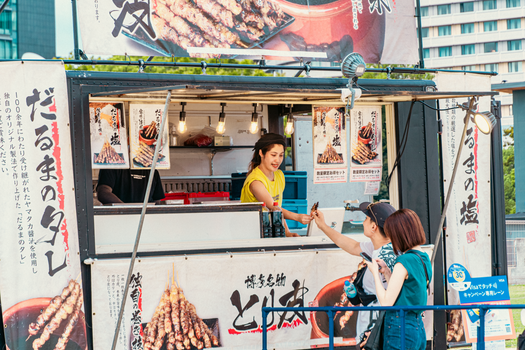 Street food vendor serves customers at a lively Japanese market.